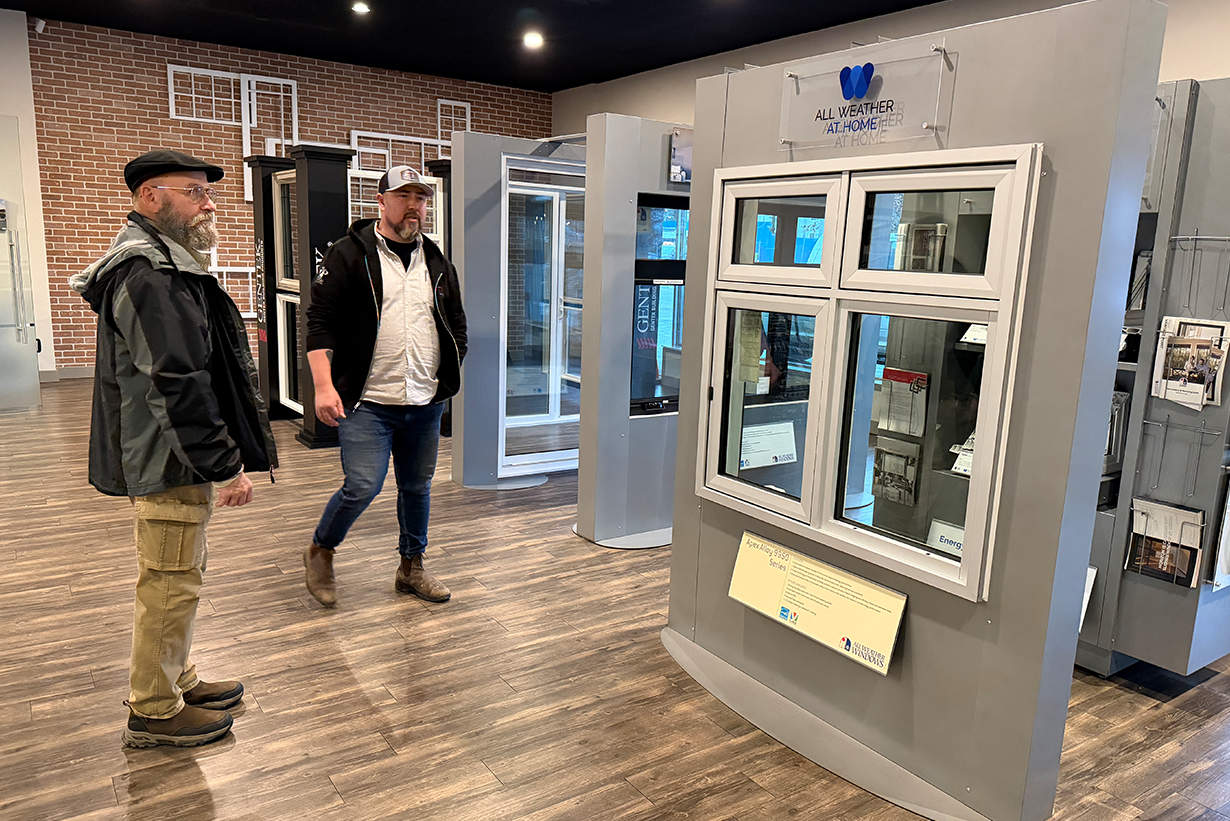 Two men examining replacement window models inside the Unger Window & Door showroom.
